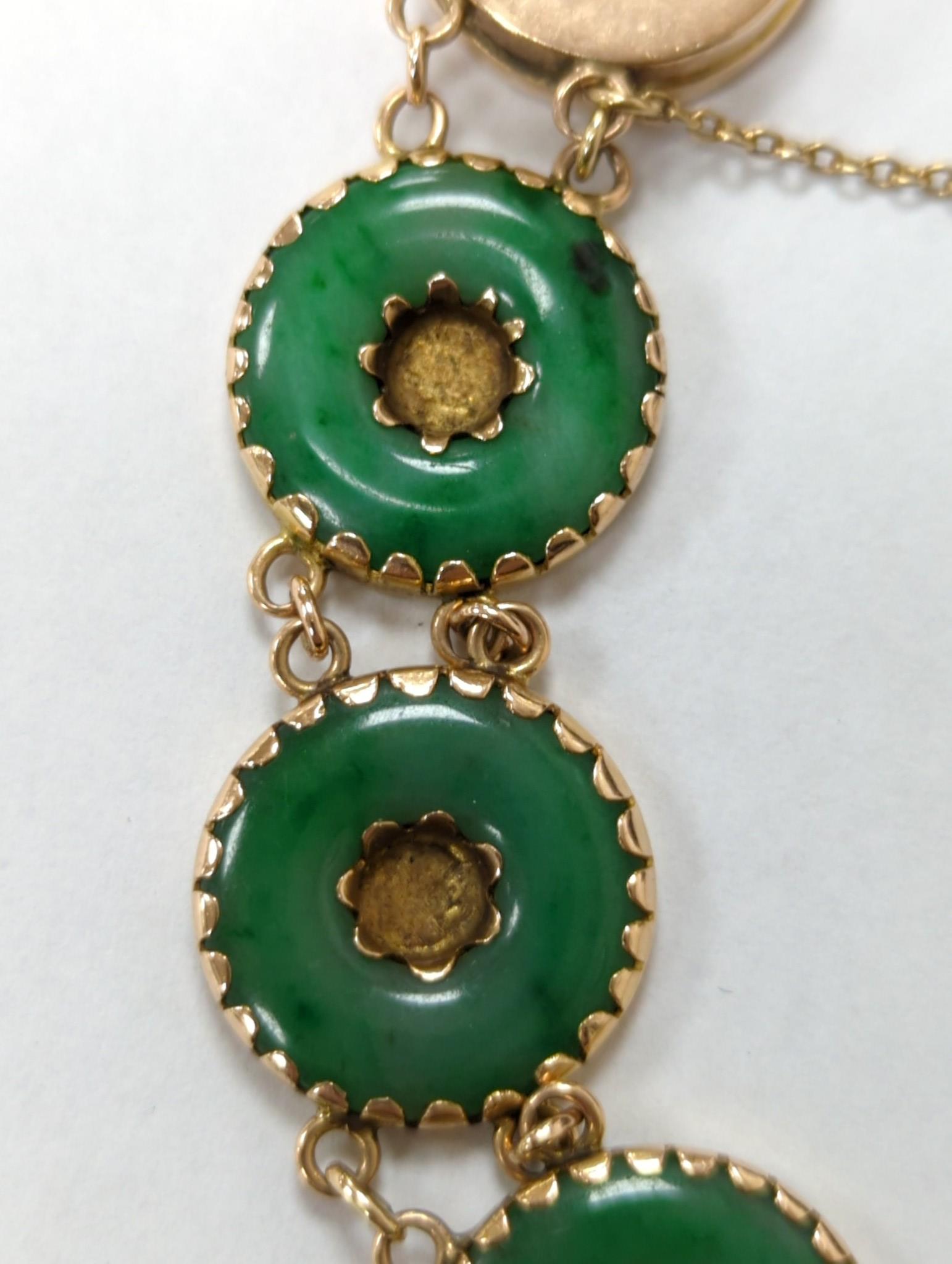 A Chinese yellow metal (stamped 18) and pierced eight stone jade disc set bracelet, with central Chinese characters, 16.5cm approx. gross weight 27.7 grams.